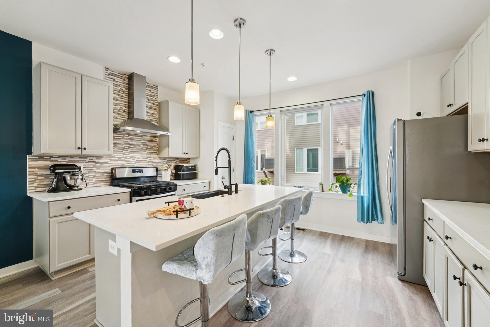 1410 Bexley Lane Frederick, MD 21701 - Photo 15 of 34 a kitchen with stainless steel appliances kitchen island granite countertop a refrigerator a stove a sink a dining table and chairs with wooden floor