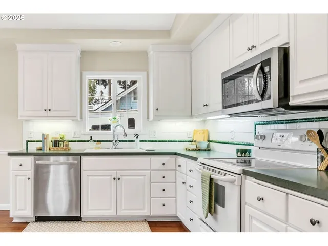 a kitchen with granite countertop white cabinets stainless steel appliances and a sink