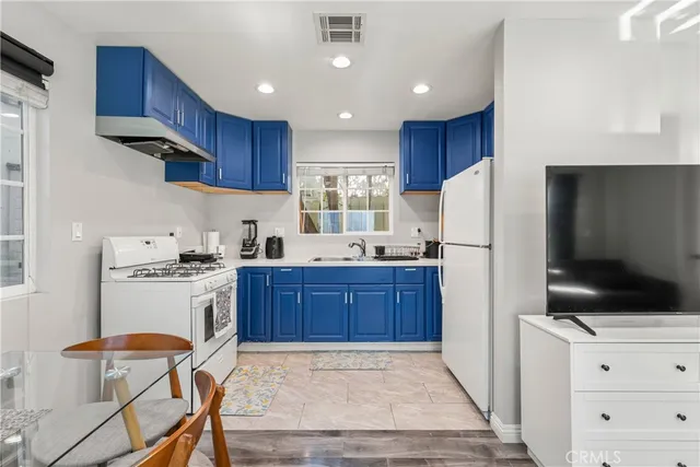 a kitchen with stainless steel appliances granite countertop a refrigerator stove a sink dishwasher and wooden cabinets with wooden floor