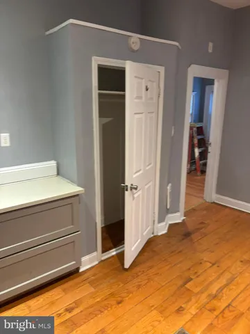 an empty room with wooden floor cabinet and windows