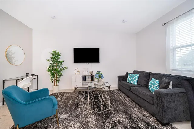 a living room with furniture a flat screen tv and a large window