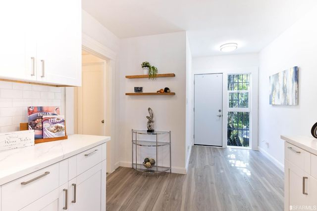 a view of a hallway to a livingroom with wooden floor and a bedroom