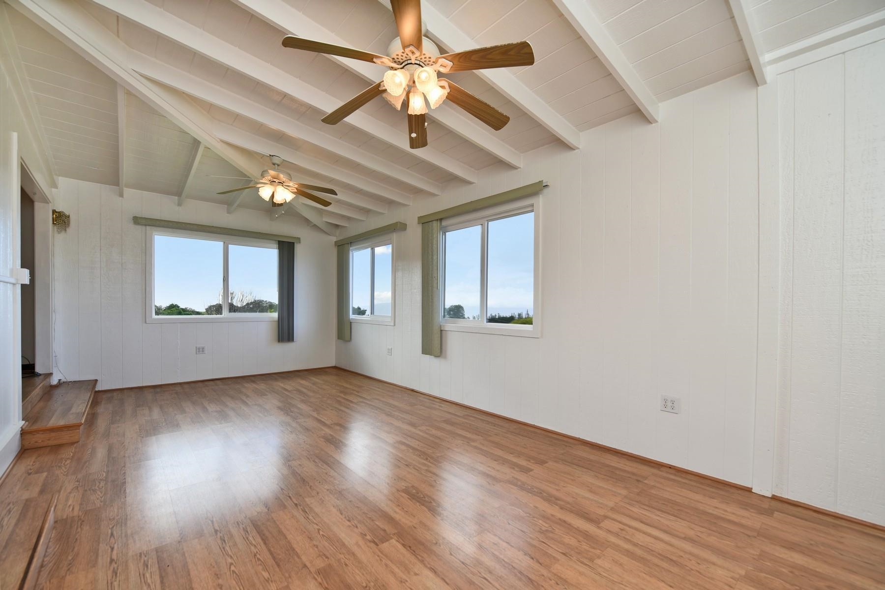 1145 Olinda Road Makawao, HI 96768 - Photo 9 of 30 an empty room with wooden floor chandelier fan and windows