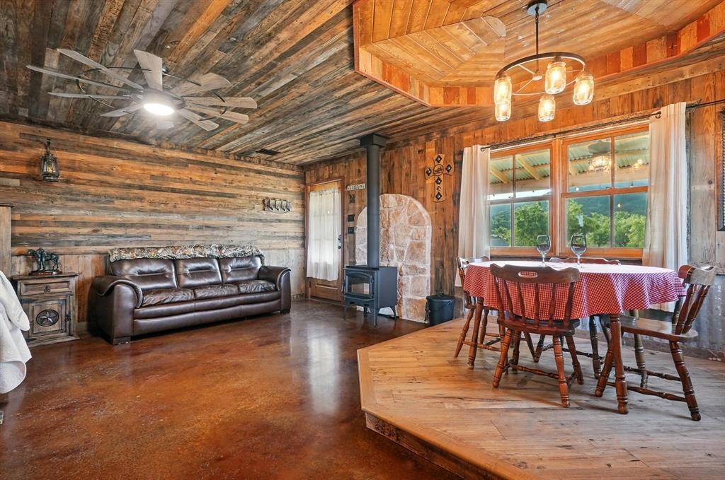 635 County Road 184 Winters, TX 79567 - Photo 18 of 40 Dining space with a wood stove, wooden walls, a ceiling fan, concrete floors, and wood ceiling