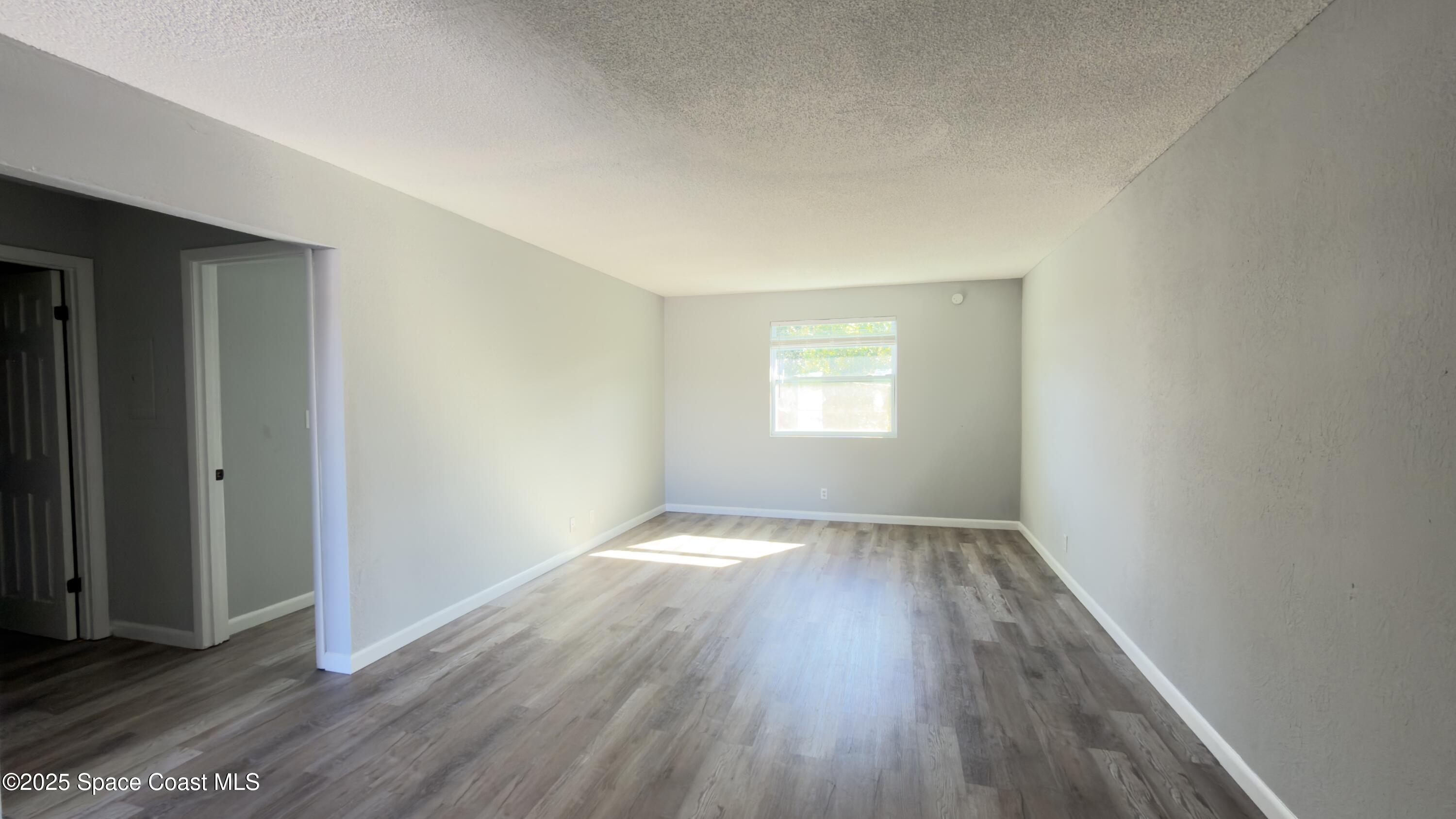4160 Barna Avenue, Unit C Titusville, FL 32780 - Photo 7 of 14 an empty room with wooden floor and windows