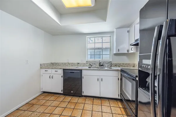 a kitchen with granite countertop a sink stove and refrigerator