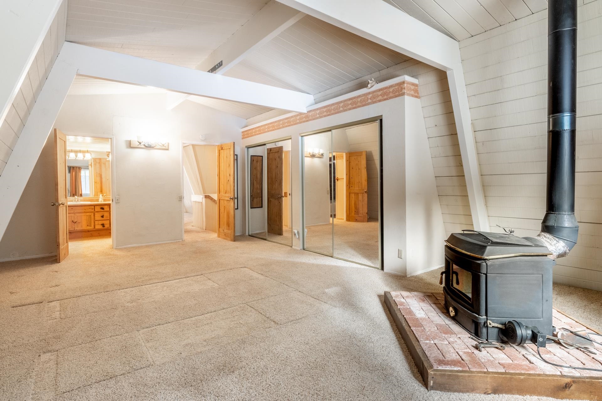 64 Mill Street Mammoth Lakes, CA 93546 - Photo 13 of 27 Unfurnished bedroom with a wood stove, two closets, carpet flooring, connected bathroom, and wooden