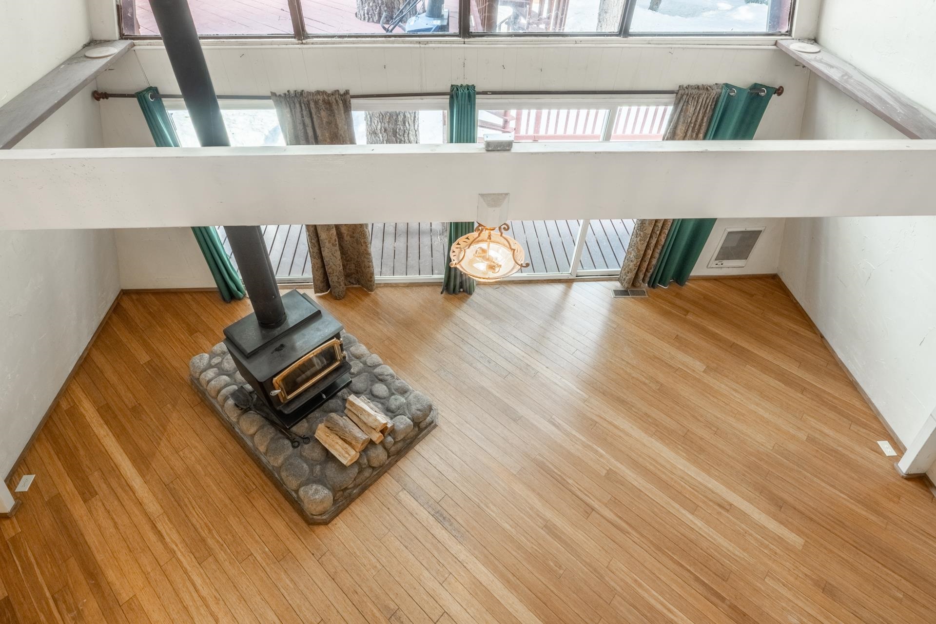 64 Mill Street Mammoth Lakes, CA 93546 - Photo 19 of 27 Unfurnished living room featuring a wood stove, light wood-type flooring, a towering ceiling, and he