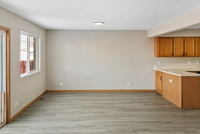 a view of an empty room with window and wooden floor