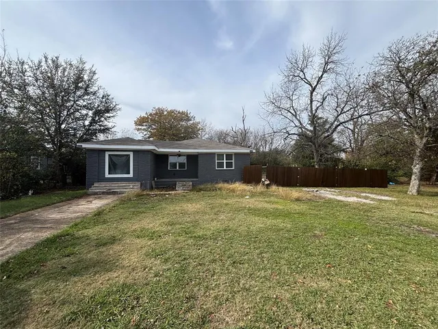 a view of a yard in front of a house with large trees