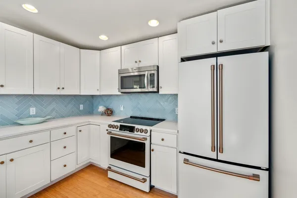a kitchen with white cabinets and white appliances