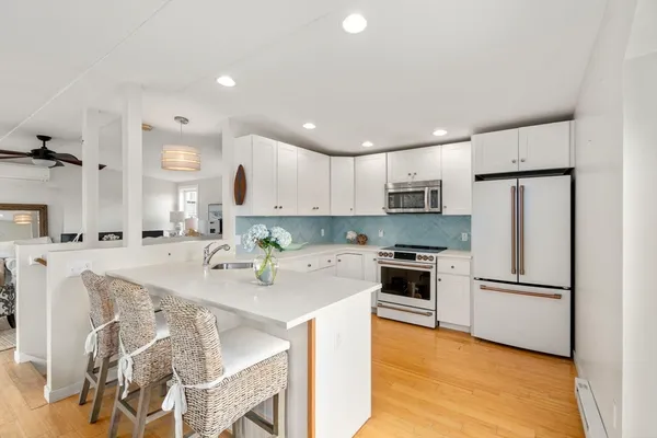 a kitchen with stainless steel appliances granite countertop a refrigerator a stove a sink dishwasher and a refrigerator with wooden floor