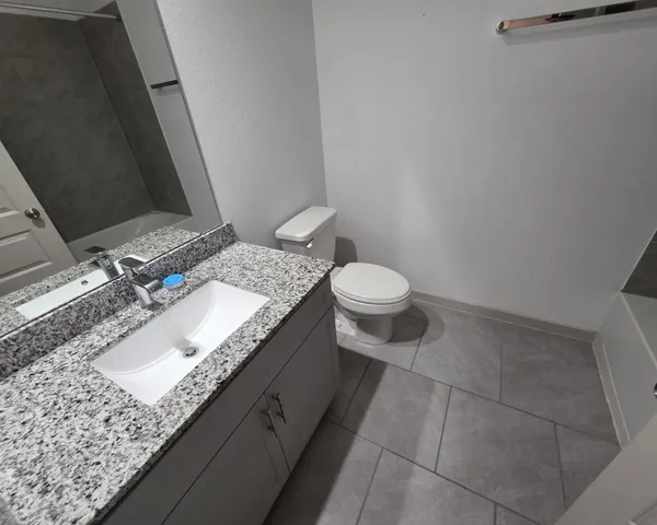 a bathroom with a granite countertop sink a mirror and a toilet