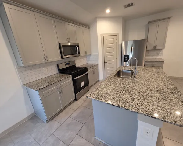 a kitchen with stainless steel appliances granite countertop a stove oven and a refrigerator
