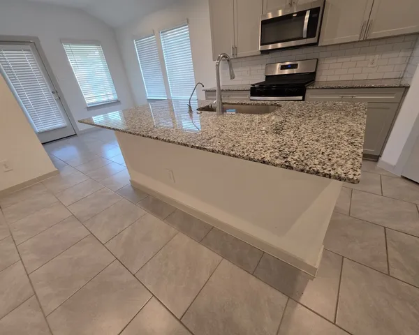 a kitchen with granite countertop a sink a stove and a microwave oven in a cabinets