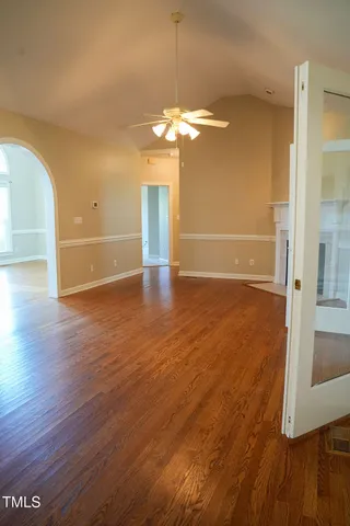 an empty room with wooden floor and windows