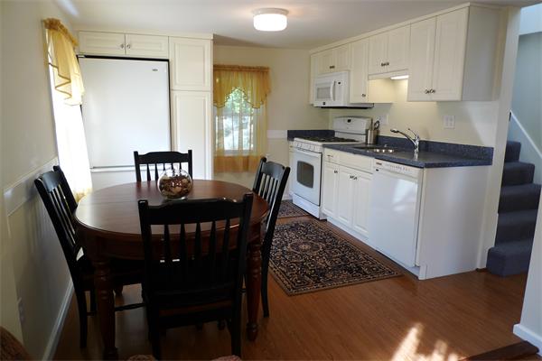 323 Appleton Street Arlington, MA 02476 - Photo 3 of 9 a kitchen with stainless steel appliances granite countertop a dining table chairs and a refrigerator
