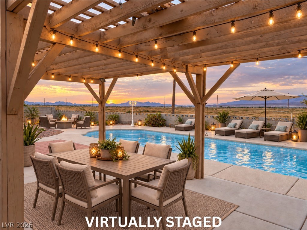 5470 Grain Mill Road Pahrump, NV 89061 - Photo 58 of 80 VIRTUALLY STAGED. Imagine the possibilities of making this your own!
A spacious poolside patio features a classic wooden pergola overlooking a desert sunset landscape.