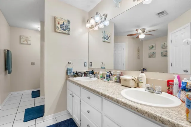 a bathroom with a granite countertop double vanity sink a mirror and shower