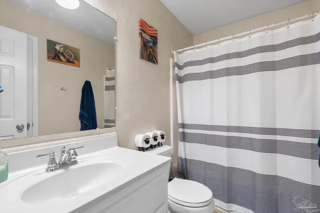 a bathroom with a sink a toilet and shower curtain