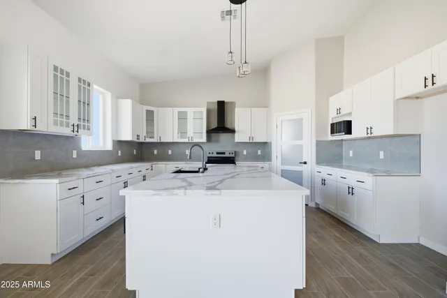 a view of a room with wooden floor a ceiling fan and kitchen space