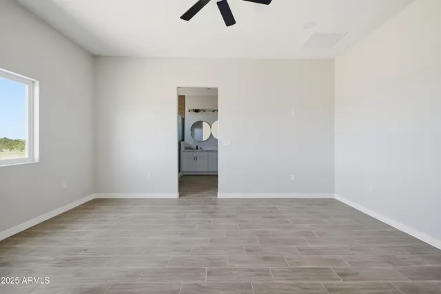 an empty room with wooden floor ceiling fan and windows