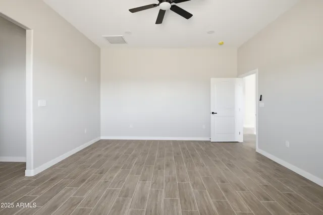 an empty room with a hardwood and ceiling fan