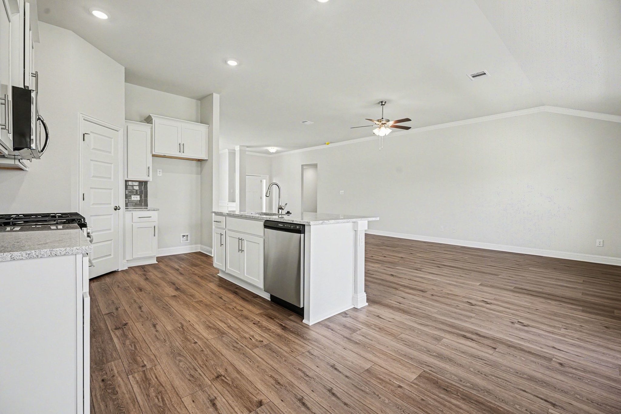 5 Keystone Court Angleton, TX 77515 - Photo 13 of 33 a large white kitchen with kitchen island a sink a stove a refrigerator and white cabinets with wooden floor