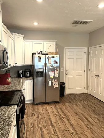 a kitchen with stainless steel appliances granite countertop a refrigerator a sink dishwasher a stove and white countertops with wooden floor