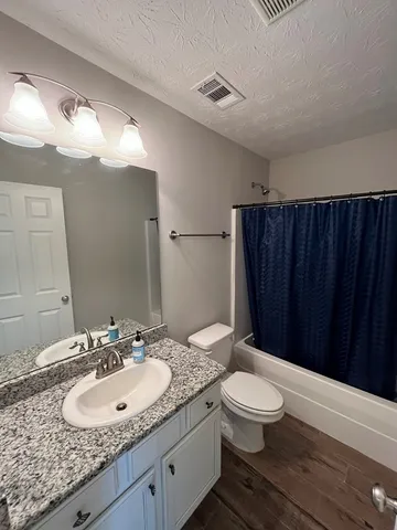 a bathroom with a granite countertop sink toilet a mirror and shower
