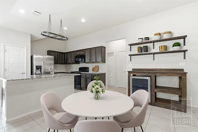 a kitchen with stainless steel appliances kitchen island granite countertop a stove a kitchen island with chairs and white cabinets