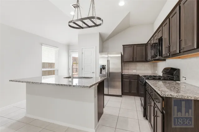 a kitchen with stainless steel appliances granite countertop a sink a stove a refrigerator cabinets and chairs