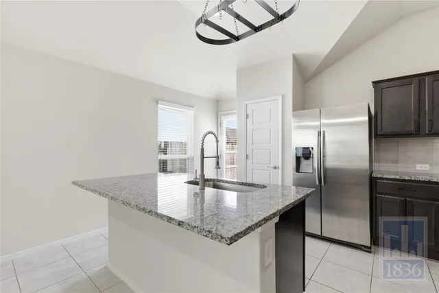 a kitchen with stainless steel appliances granite countertop a sink and a refrigerator