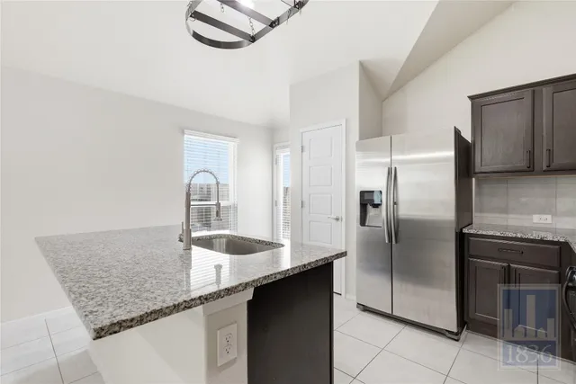 a kitchen with granite countertop a sink and a refrigerator