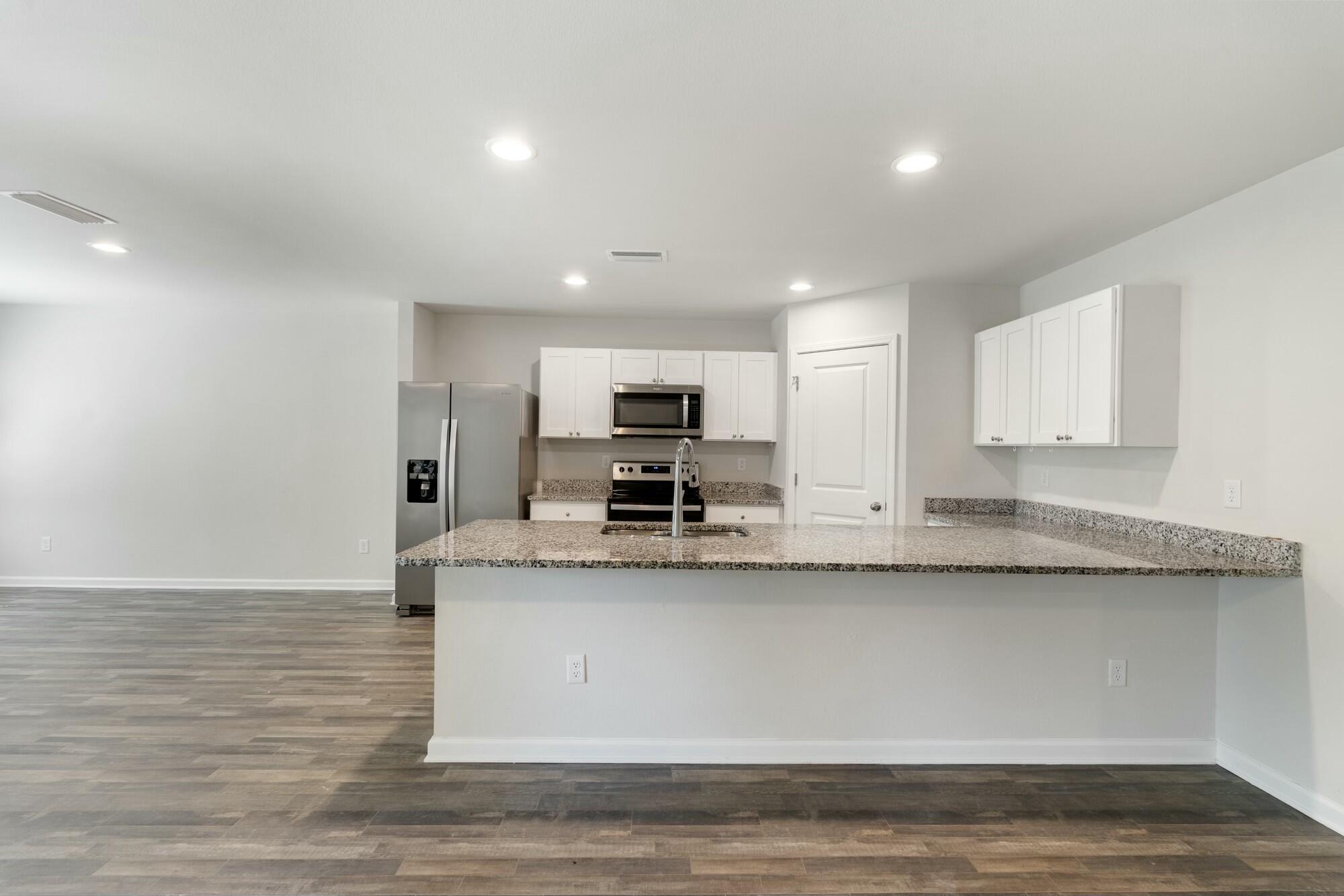 610 Riverwalk Circle Freeport, FL 32439 - Photo 14 of 50 a large kitchen with granite countertop a sink and a stove top oven with wooden floor