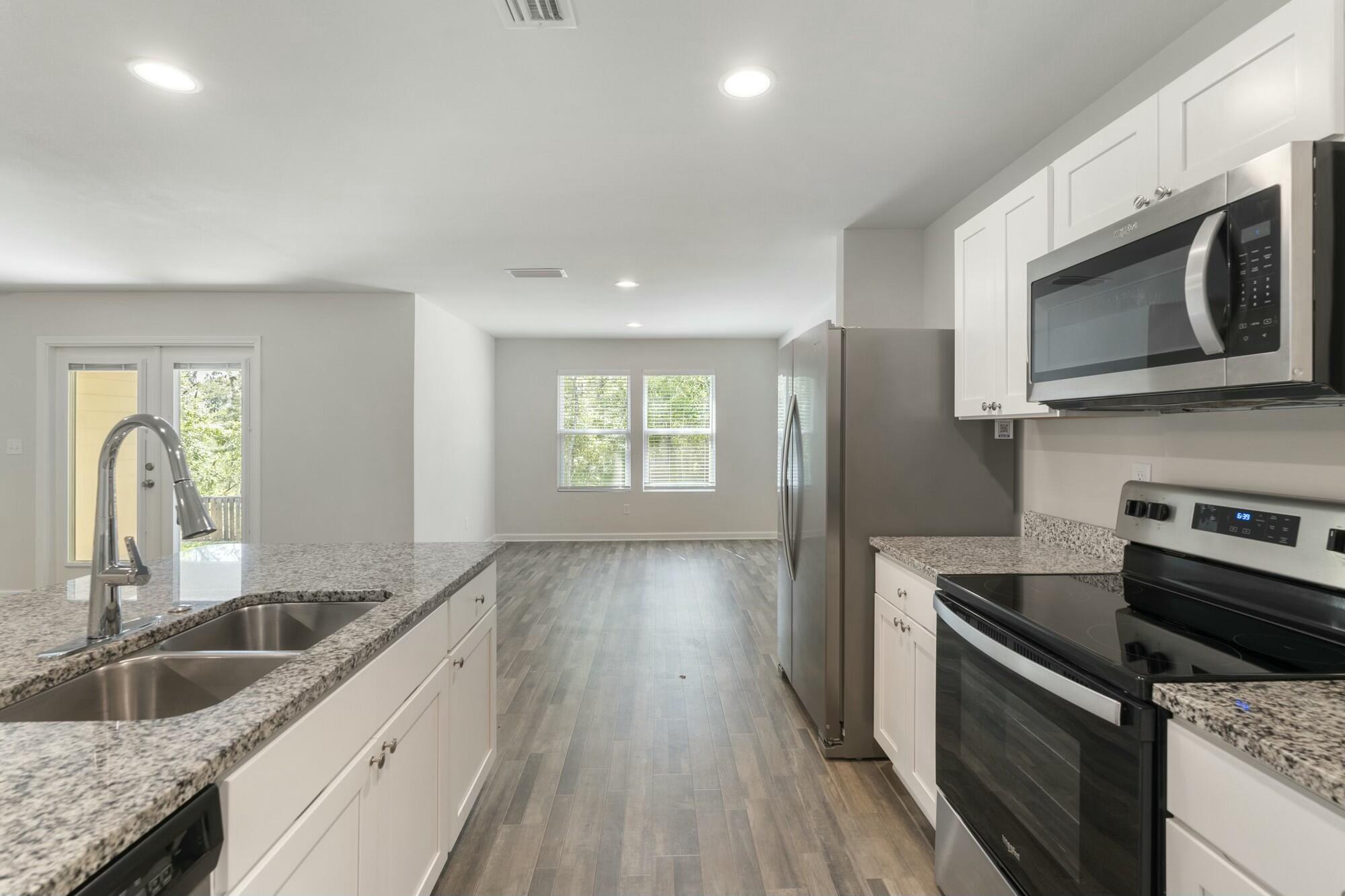 610 Riverwalk Circle Freeport, FL 32439 - Photo 17 of 50 a kitchen with granite countertop a sink wooden floor and stainless steel appliances
