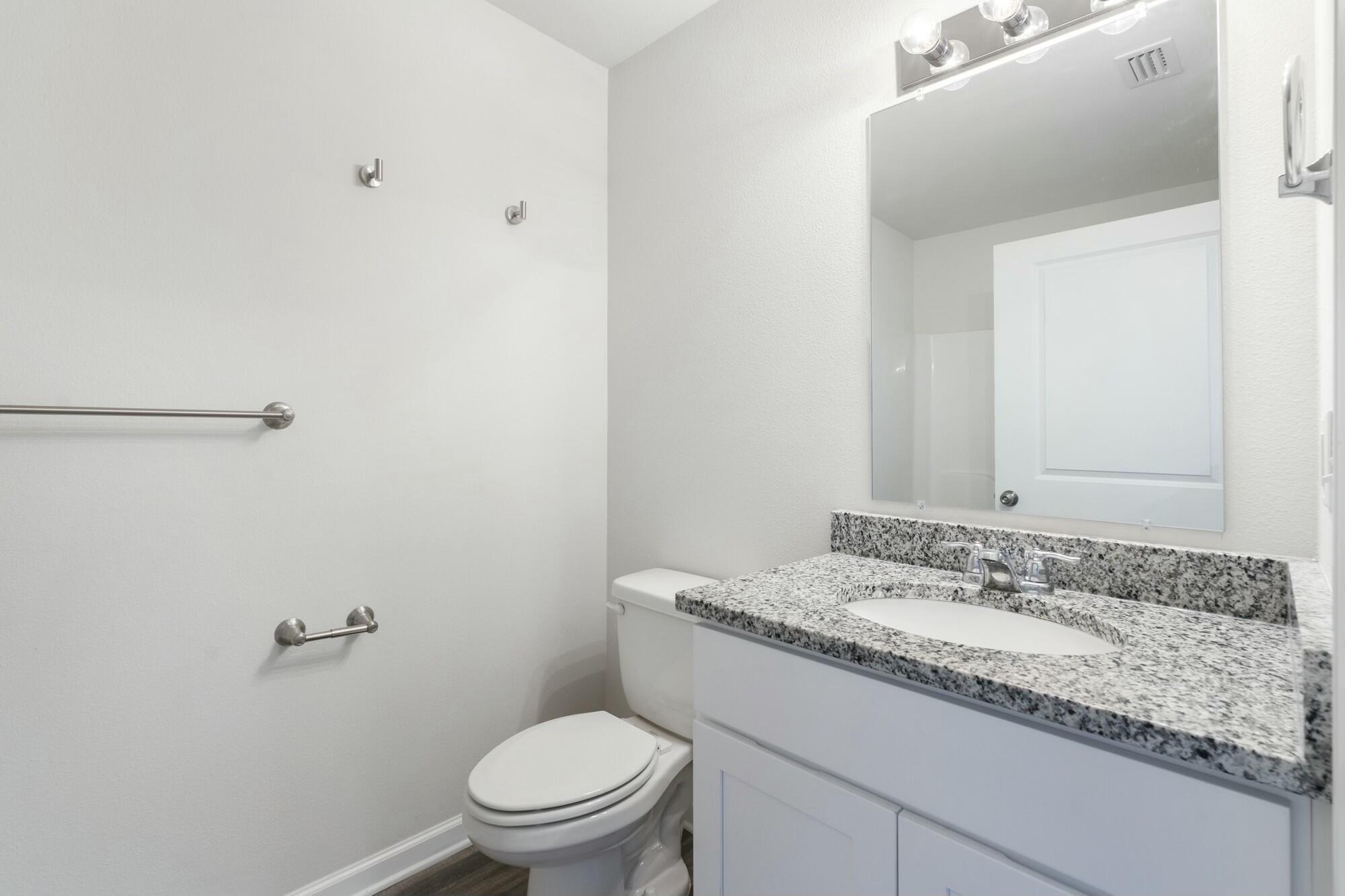 610 Riverwalk Circle Freeport, FL 32439 - Photo 34 of 50 a bathroom with a granite countertop sink a toilet and a mirror