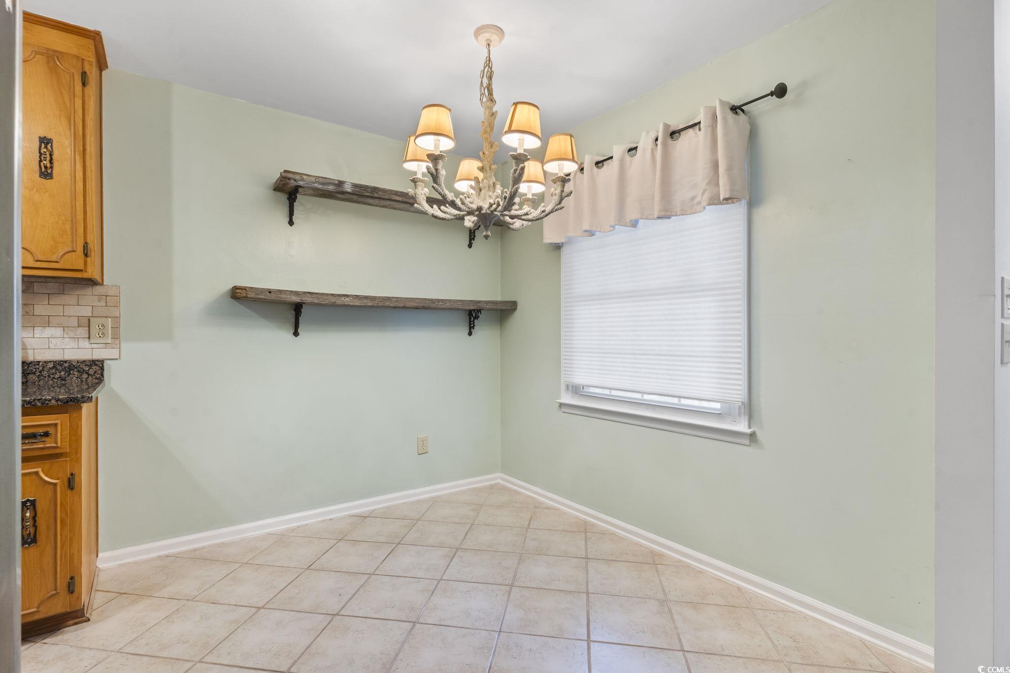 210 25th Avenue South, Unit 13 Myrtle Beach, SC 29577 - Photo 2 of 10 Unfurnished dining area with light tile patterned flooring and a chandelier