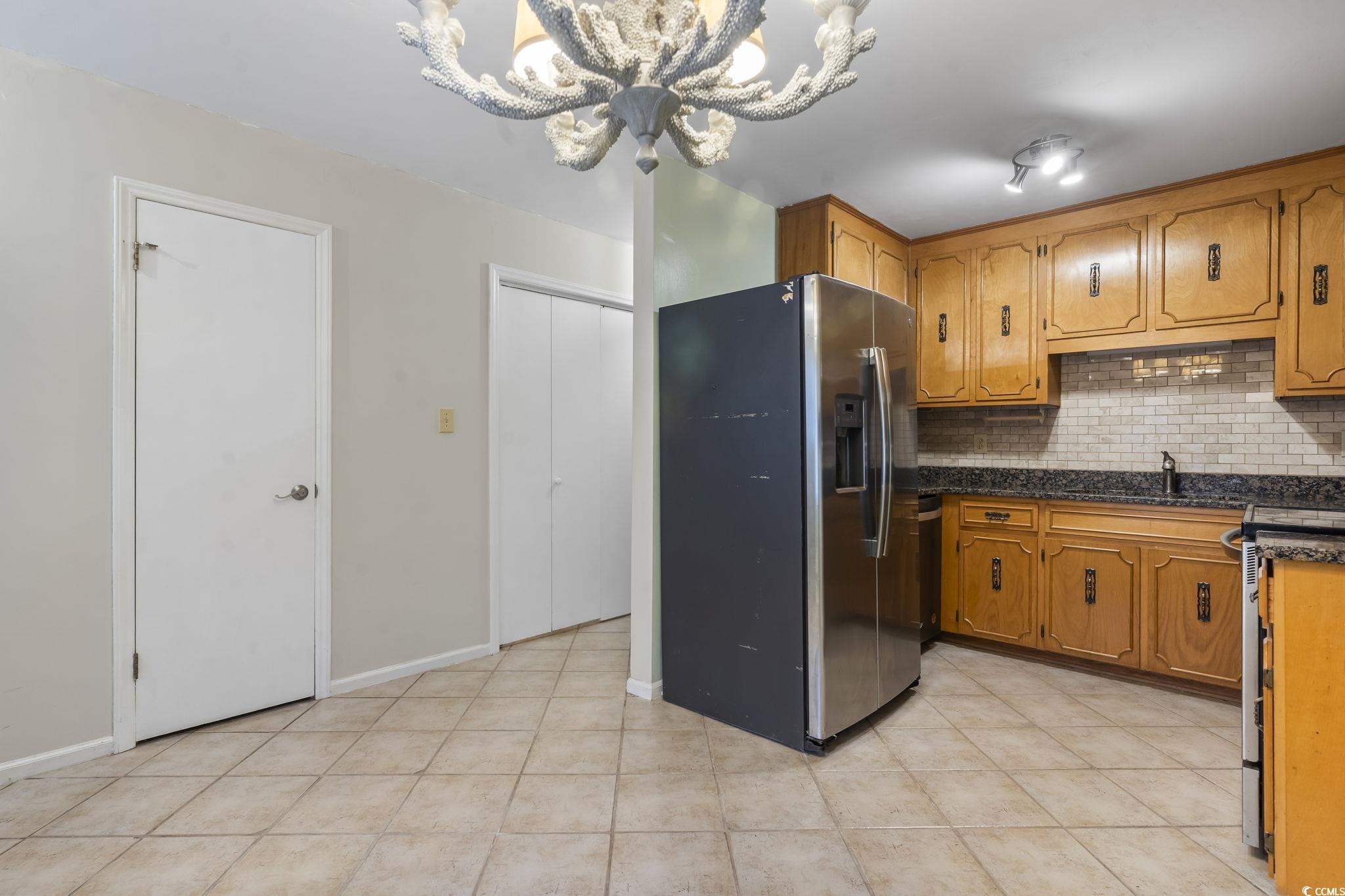 210 25th Avenue South, Unit 13 Myrtle Beach, SC 29577 - Photo 3 of 10 Kitchen featuring stainless steel appliances, decorative backsplash, brown cabinets, and a chandelier