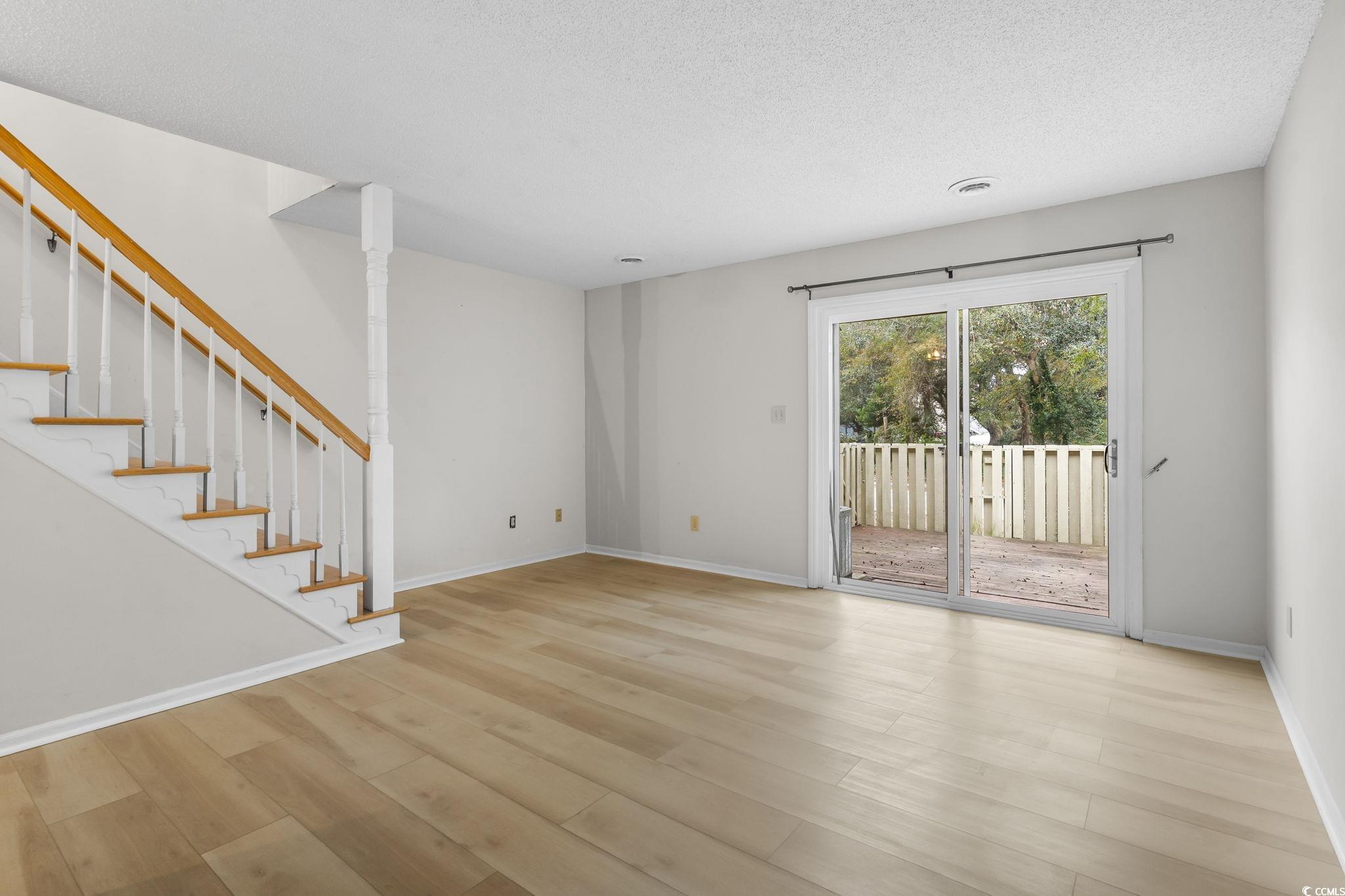210 25th Avenue South, Unit 13 Myrtle Beach, SC 29577 - Photo 7 of 10 Unfurnished room with stairway, light wood finished floors, and a textured ceiling