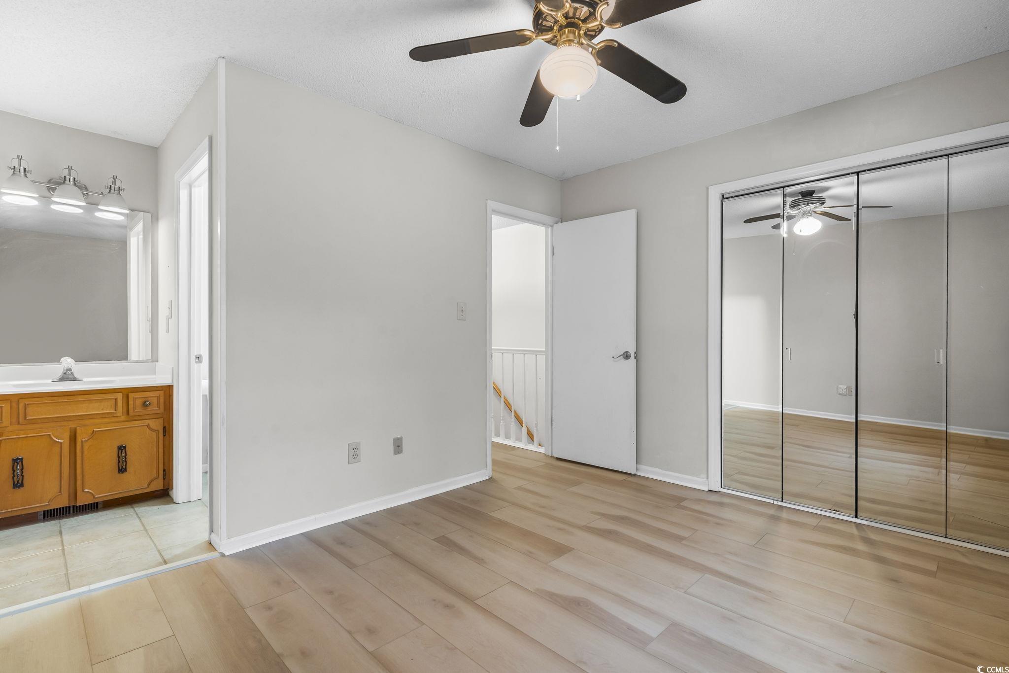 210 25th Avenue South, Unit 13 Myrtle Beach, SC 29577 - Photo 9 of 10 Unfurnished bedroom featuring ensuite bathroom, light wood-type flooring, a ceiling fan, and a closet
