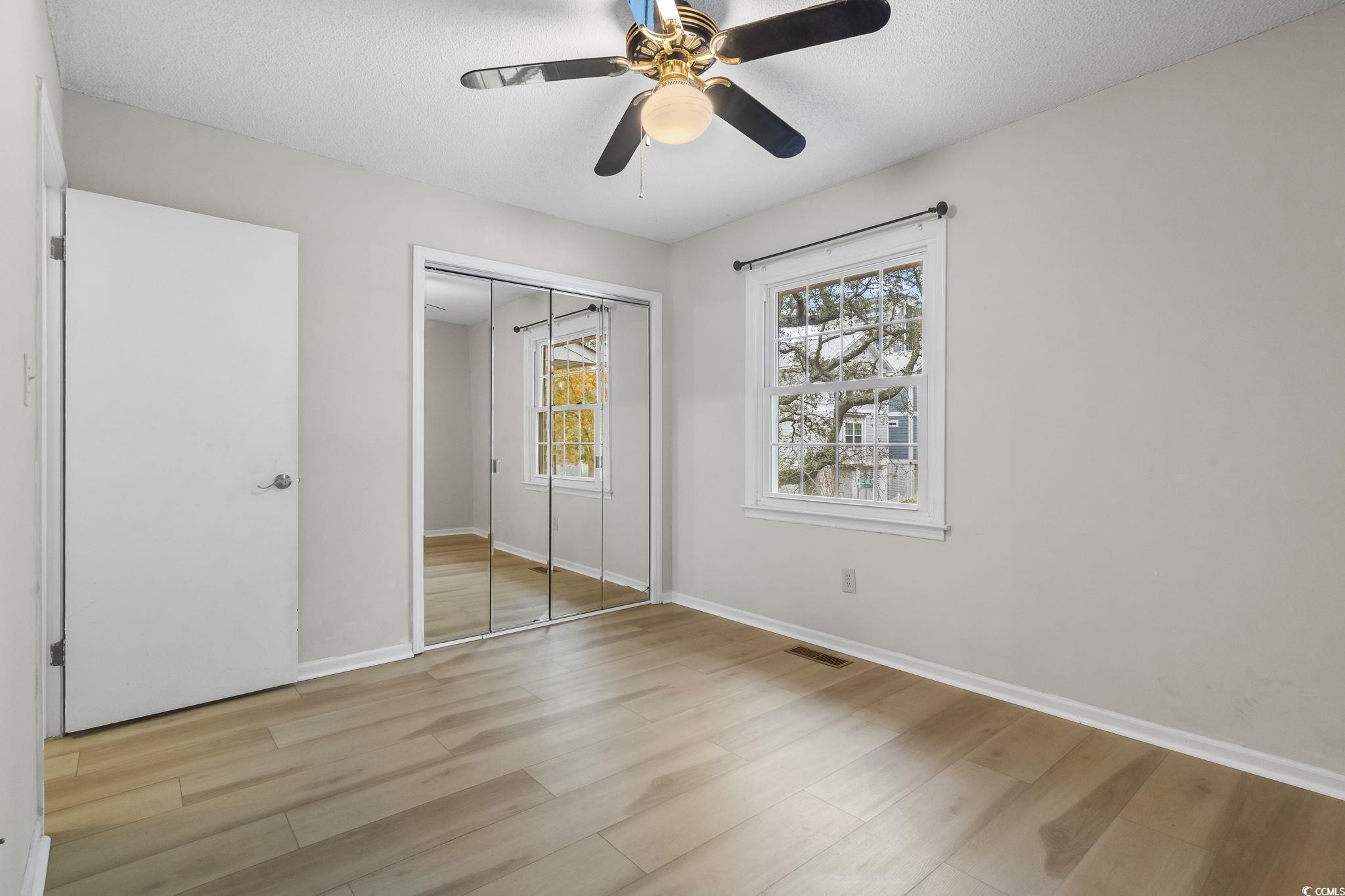 210 25th Avenue South, Unit 13 Myrtle Beach, SC 29577 - Photo 10 of 10 Unfurnished bedroom featuring light wood-type flooring, a closet, a ceiling fan, and a textured ceiling