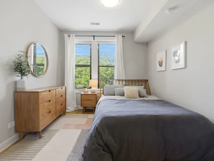 a bedroom with a bed and a dresser next to a window