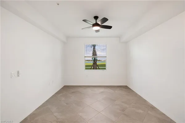 an empty room with windows and ceiling fan