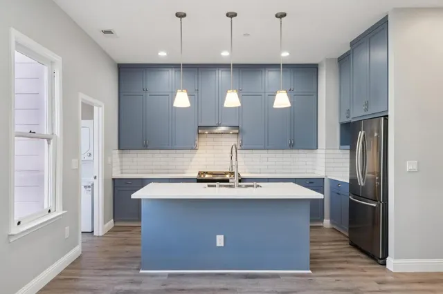 a view of a kitchen with stainless steel appliances granite countertop a stove a refrigerator and a sink with wooden floor