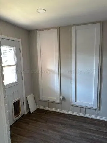 an empty room with wooden floor fireplace and windows