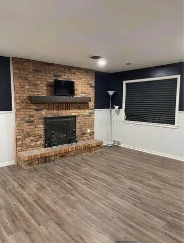a view of an empty room with wooden floor and a fireplace