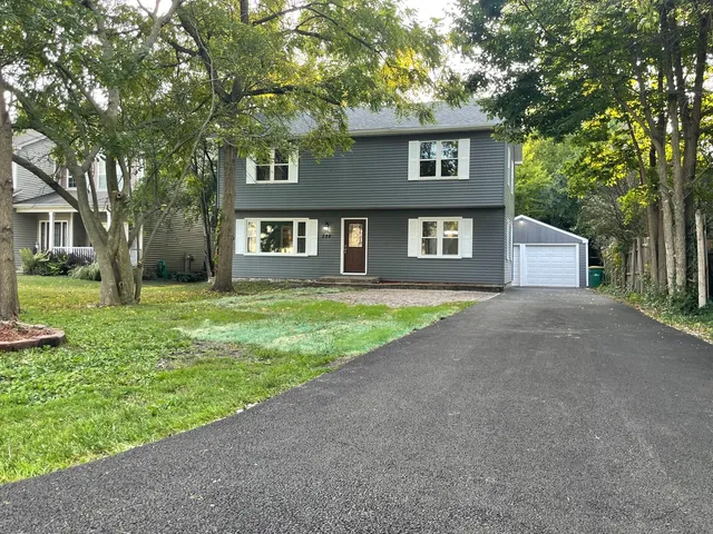 a front view of a house with a yard and trees