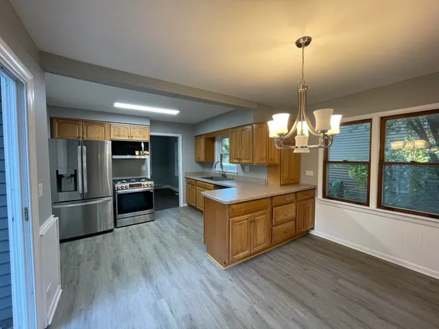 a large kitchen with stainless steel appliances granite countertop a refrigerator a oven a island and a wooden floor