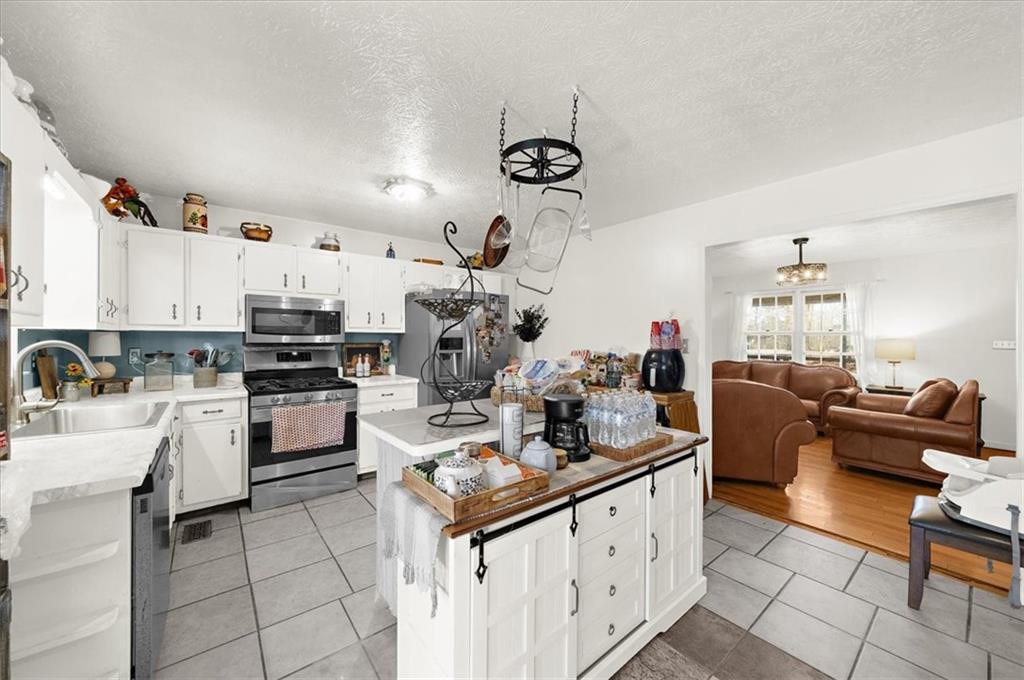 1059 Old Alabama Road Southwest Mableton, GA 30126 - Photo 14 of 33 a kitchen with kitchen island granite countertop lots of white cabinets a sink dishwasher and a stove with wooden floor